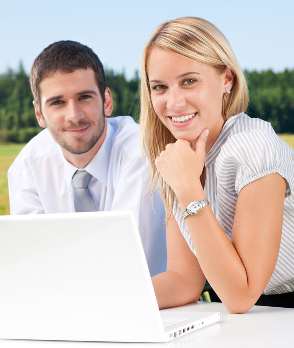 Young business people sitting outside by office desk with with laptop