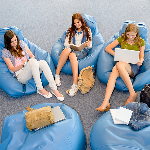Teenage students sitting on beanbags and studying in library